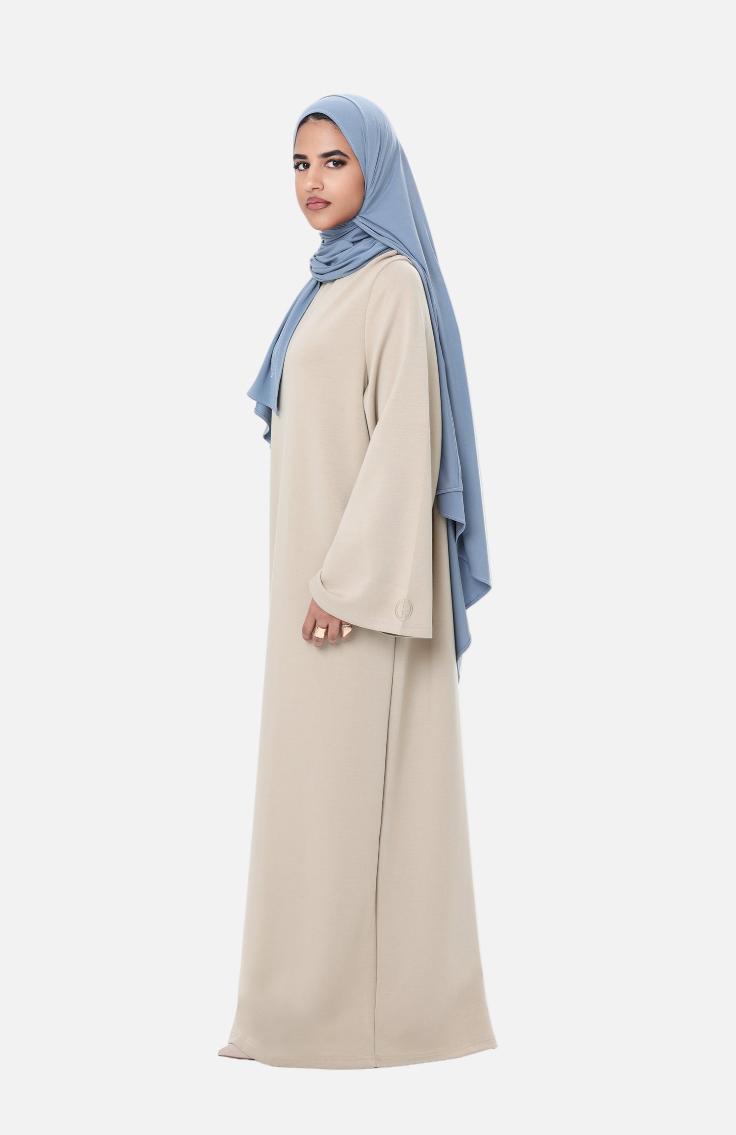 Front-side view of the Comfy Dress in Beige styled with a light blue hijab, showing the effortless and elegant silhouette.