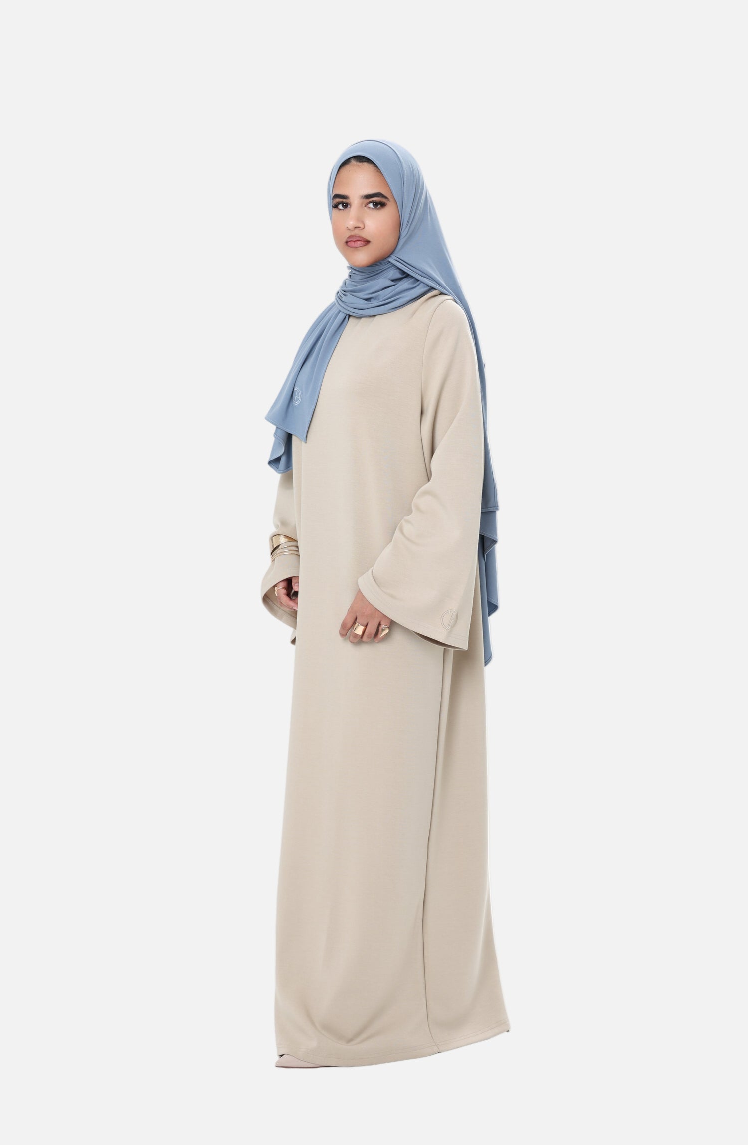 Side view of model wearing the Comfy Dress in Beige with a light blue hijab, showcasing the relaxed modest fit and soft drape.