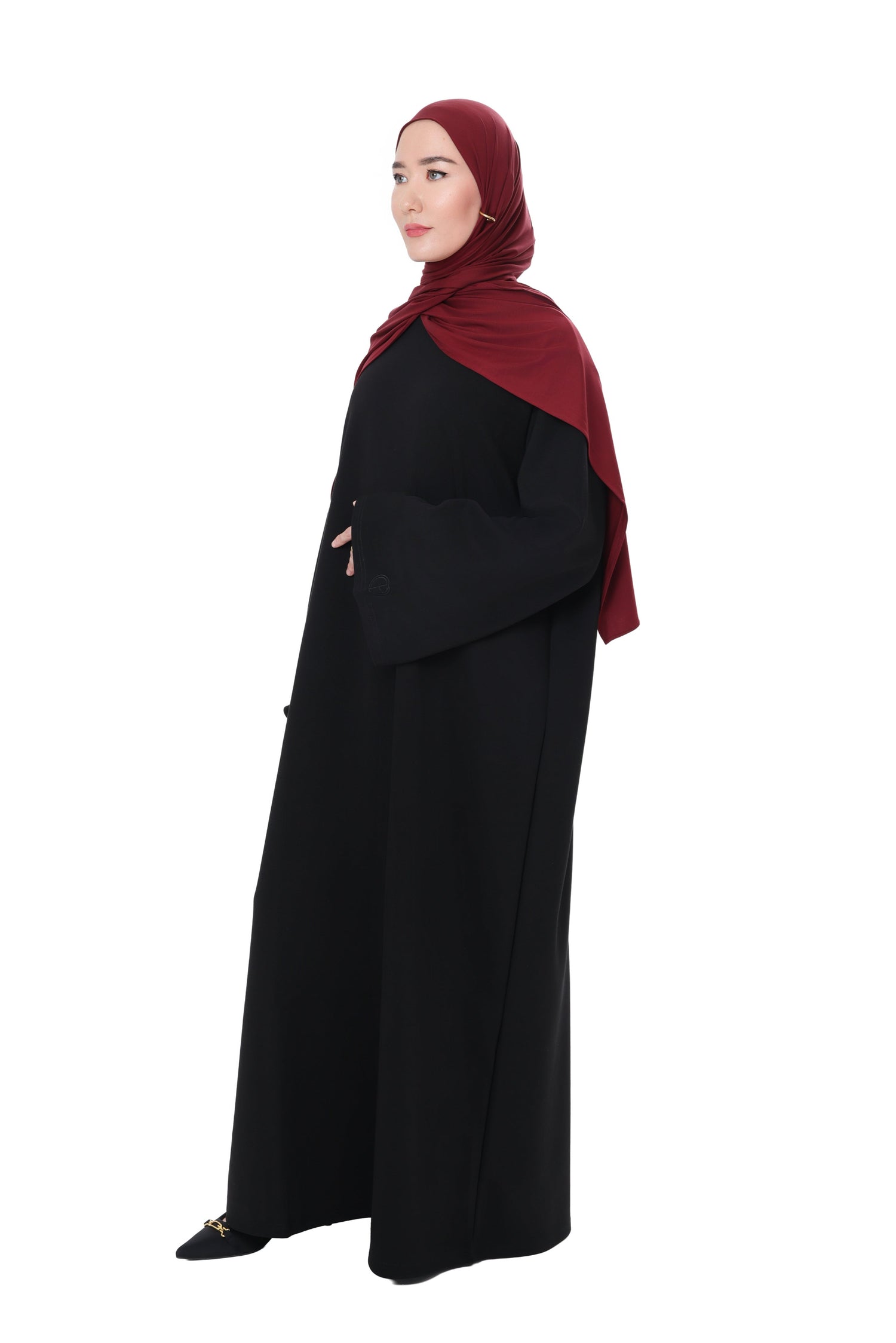 Model wearing the Comfy Dress in Black styled with a deep burgundy hijab, side view showcasing the relaxed oversized fit and wide sleeves.