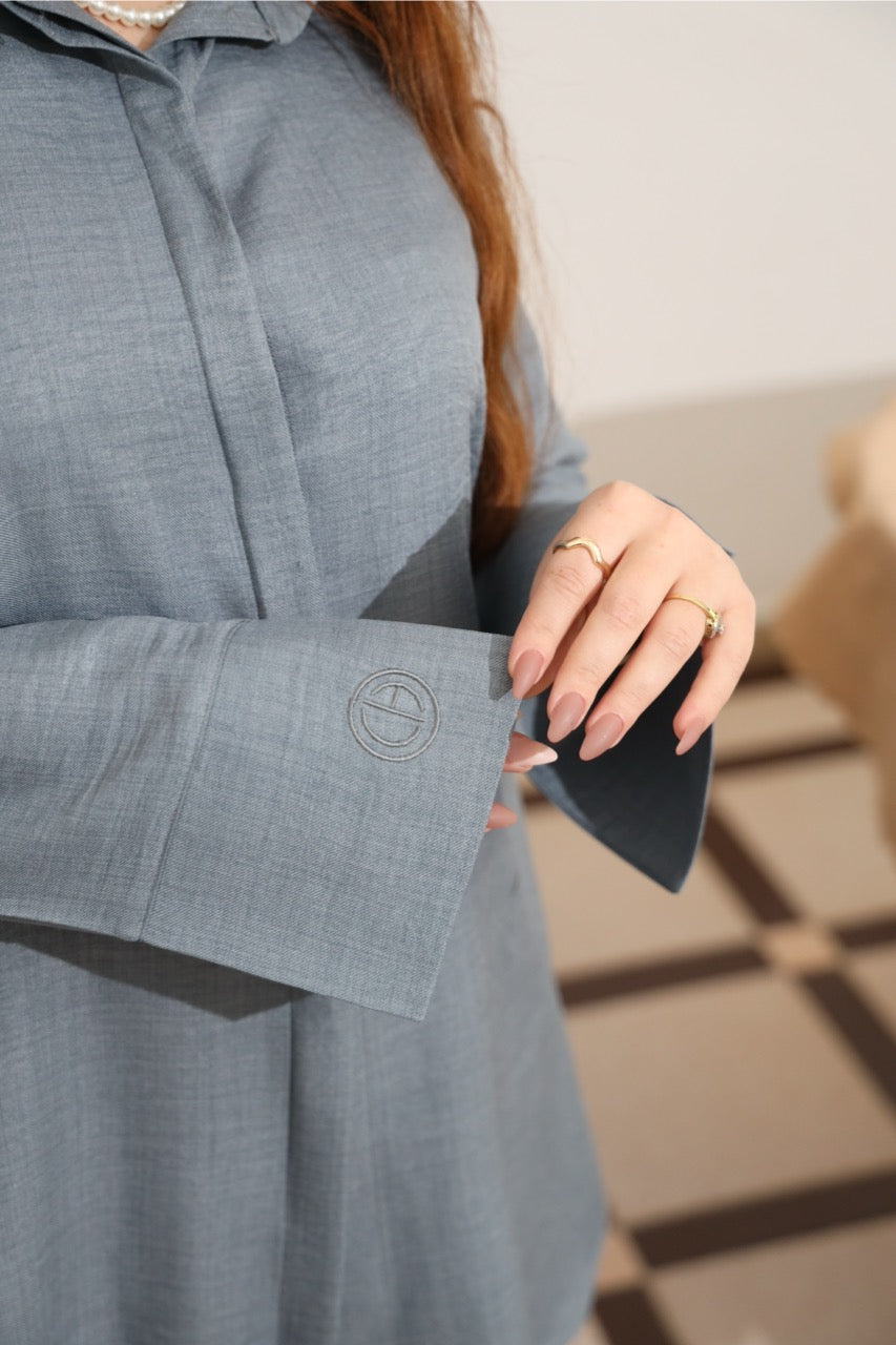 Close-up of the sleeve with embroidery logo of the steel blue tunic. 
