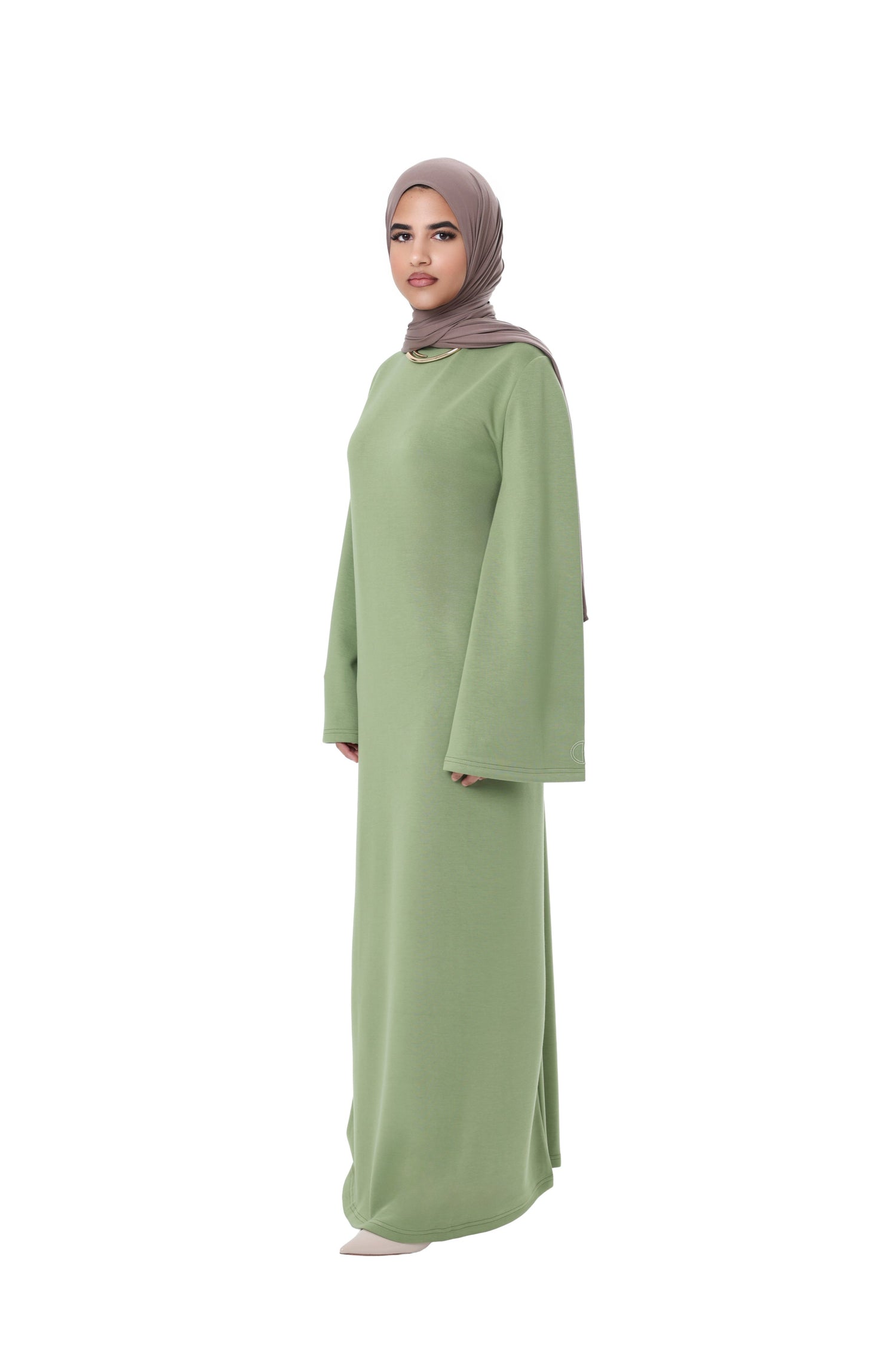 Side view of model wearing the Comfy Dress in Olive with a taupe hijab, showcasing the relaxed modest fit and wide sleeves.